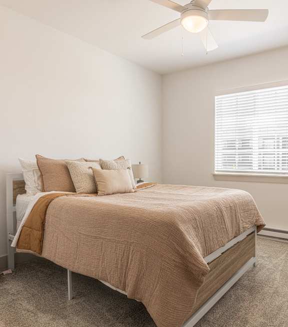 A bedroom with a bed, nightstand, and window.