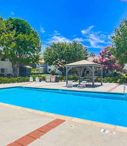 a swimming pool with a gazebo and chairs around it