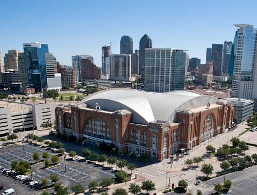 A large stadium with a dome-like roof is the focal point of the image, surrounded by a cityscape.