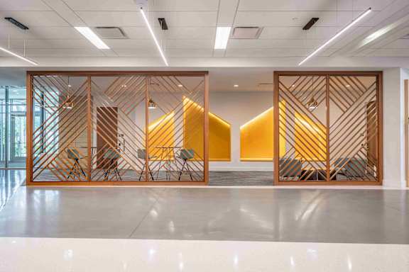 A room with a white floor and a wooden partition with a geometric pattern.