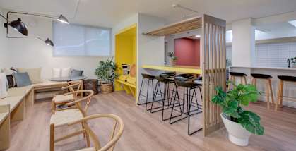 A room with a yellow door and a bar area with stools.