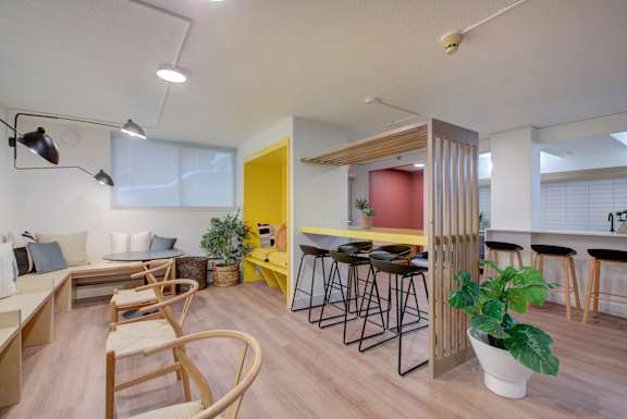  A room with a yellow door and a bar area with stools.