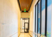 Thumbnail 13 of 23 - a corridor in a building with large windows and a wooden ceiling