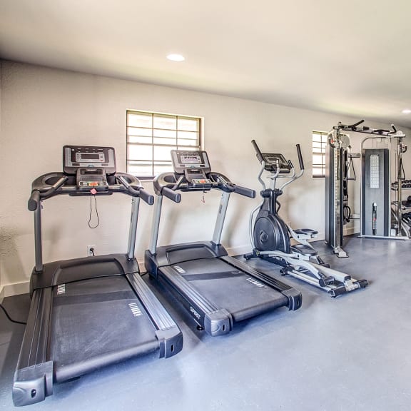 a gym with cardio equipment and weights on the floor