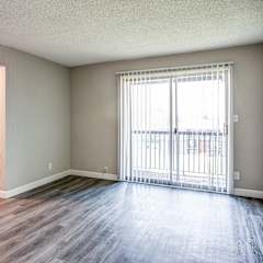 an empty living room with wood floors and a large window
