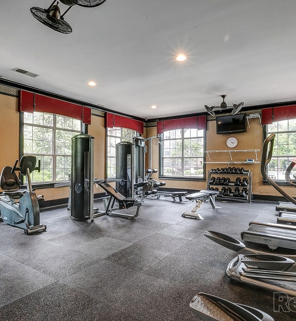 a gym with weights and cardio equipment in a room with windows