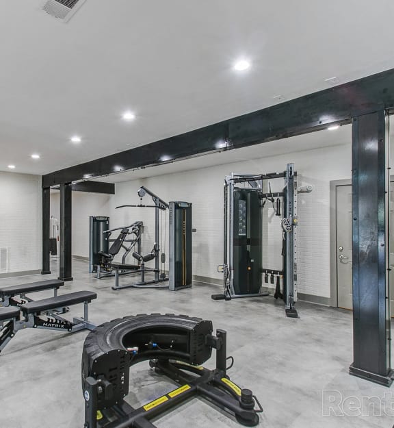 a gym with weights and other equipment in a room with white walls and a door