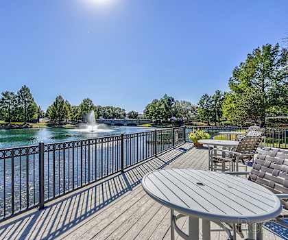 A sunny day at a park with a fountain and a deck.