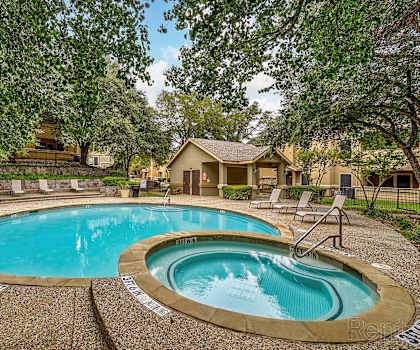 A swimming pool surrounded by trees and a house in the background.
