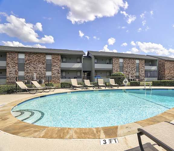 a swimming pool with lounge chairs in front of a building