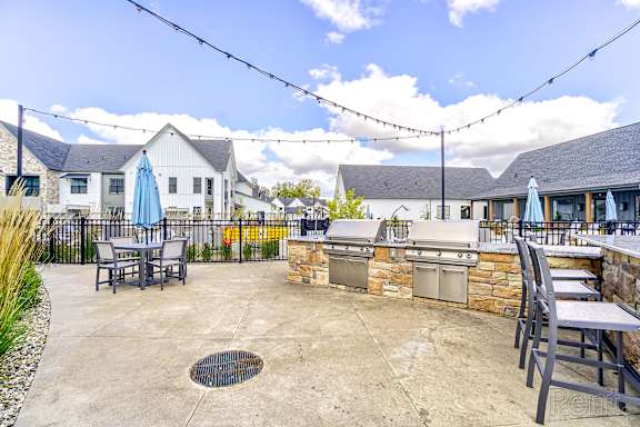 A patio with a table and chairs is surrounded by a fence and houses.