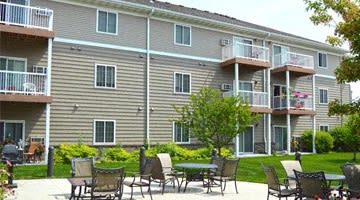an outdoor patio with tables and chairs in front of an apartment building