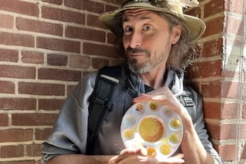 Artist Andy Jordan holding a paint palette while standing against a brick wall at The Citizen Birmingham