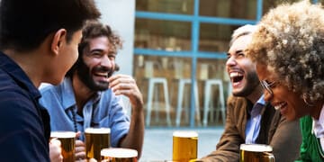 a group of people sitting around a table drinking beer