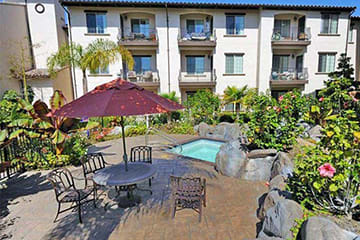 a patio with a table and an umbrella in front of an apartment building