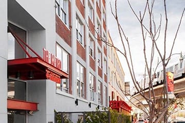 an apartment building with a red and white facade and a street