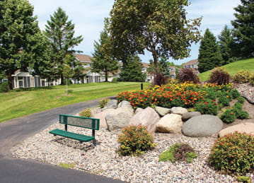 flowers, bench and walking path on grounds of Cedar Pointe