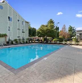 A swimming pool in front of a building surrounded by trees.