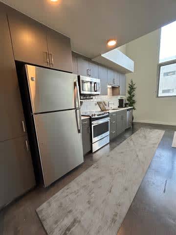 A modern kitchen with stainless steel appliances and a marble countertop.
