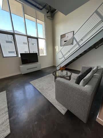 A living room with a grey couch and a television on a white stand.
