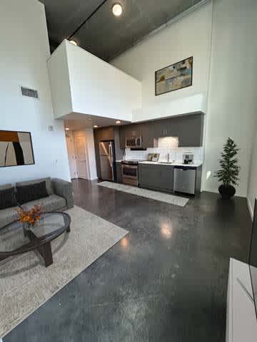 A modern living room with a grey floor and a grey couch.
