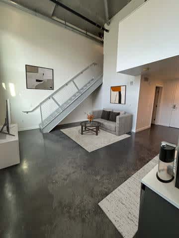 A modern living room with a grey floor and a staircase.
