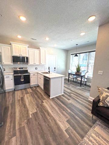 A kitchen with white cabinets and a wooden floor.