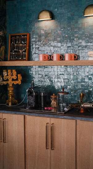 A kitchen with wooden cabinets and a shelf with cups and a picture frame. at The PARKER on E Mulberry Apartments, San Antonio, Texas