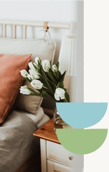a bedroom with a vase of white flowers on a table
