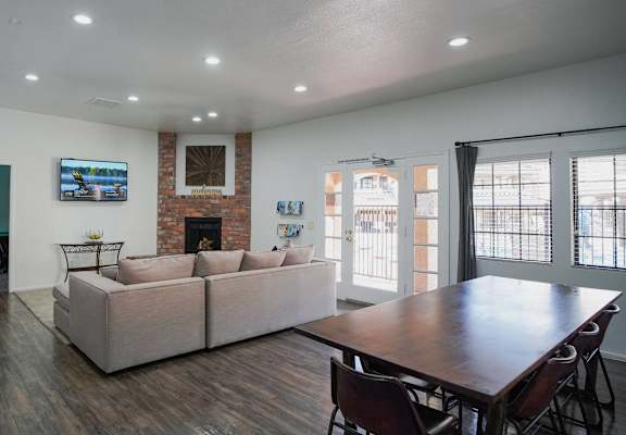 A living room with a couch, chairs, and a flat screen TV mounted on the wall.