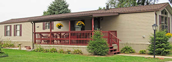 A house with a red railing and a tree in front.