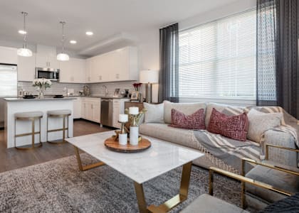 A modern kitchen with a breakfast bar and a white sofa with pink pillows.