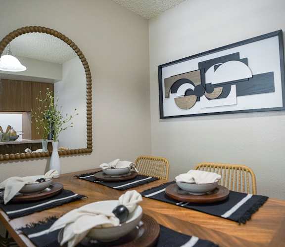 A dining room with a wooden table set for two.