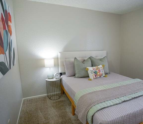 A bedroom with a bed, nightstand, and lamp.