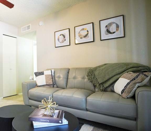 A living room with a grey couch, a coffee table, and a ceiling fan.