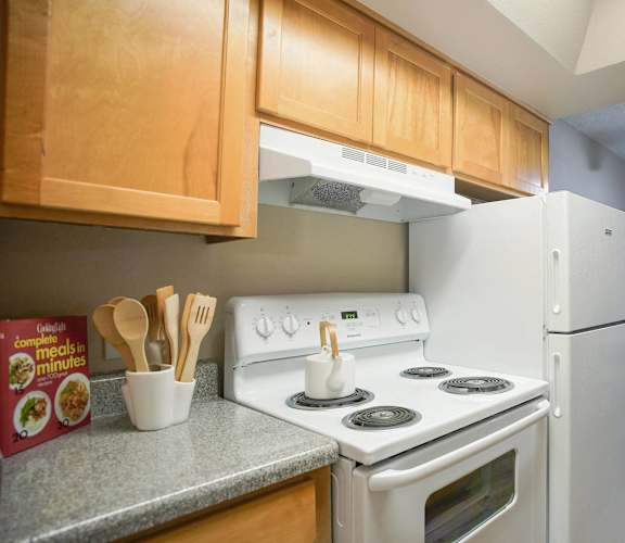 A kitchen with a white stove and refrigerator.