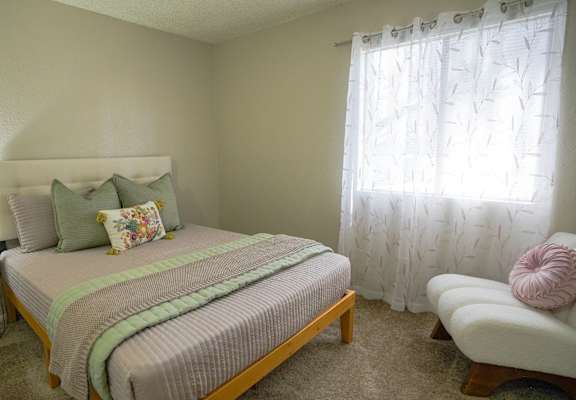 A bedroom with a bed, a chair, and a lamp.