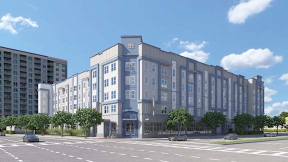 A large grey building with a blue sky and clouds in the background.
