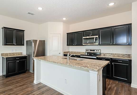a kitchen with an island and black cabinets and a stainless steel refrigerator