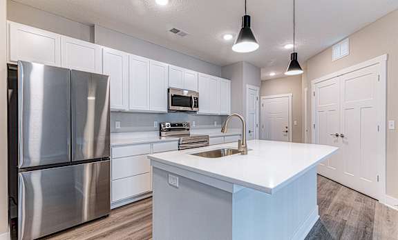 A modern kitchen with a stainless steel refrigerator and white cabinets.at Tiffany Flats, Columbus, 43231