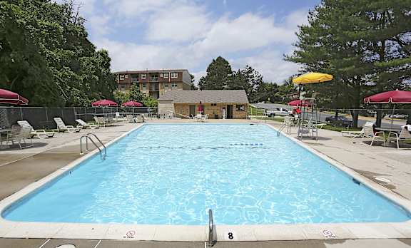 A large outdoor swimming pool with a diving board and sunshades.