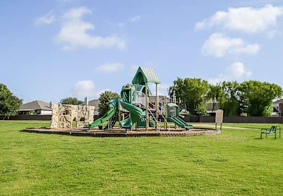 A playground with a green slide and a climbing wall.