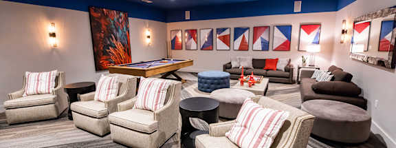 A room with a pool table and several chairs.