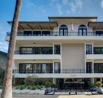 A white building with black railings and a balcony with an American flag on it.
