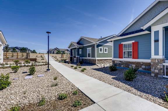 a row of blue houses with red doors and a sidewalk