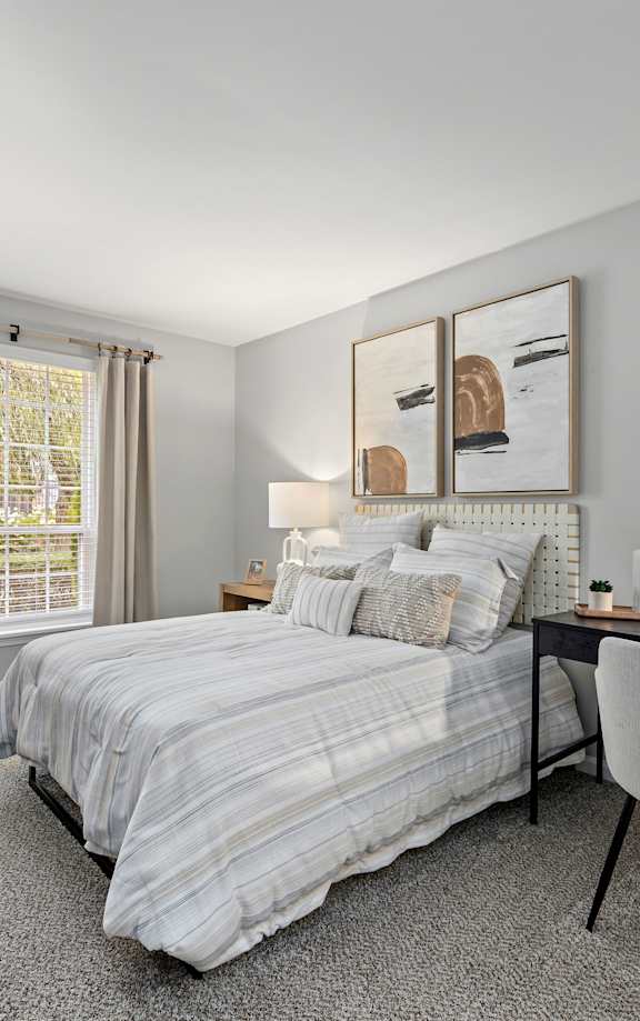 A bedroom with a bed, desk, chair, and window.
