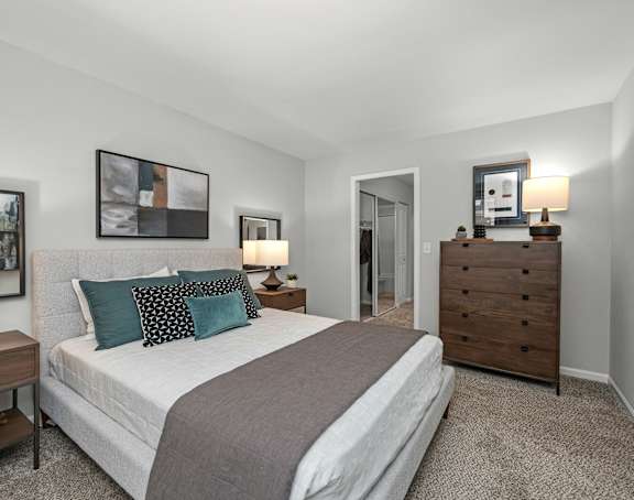A bedroom with a bed, nightstands, and a painting on the wall.