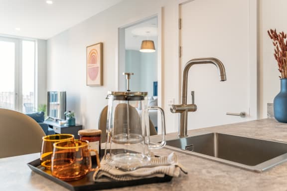 a kitchen counter with a sink and a faucet and a tray of glasses