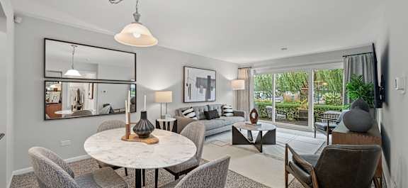 A modern dining room with a round table and grey chairs.