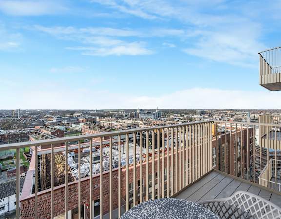 the view of the city from the balcony of a building with chairs and a table
